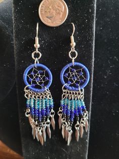 a pair of earrings sitting on top of a table next to a dime penny coin