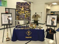 two police officers standing next to a table with pictures on it and plaques about their roles