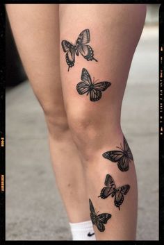 a woman's legs with black butterflies on them and one is showing off her leg