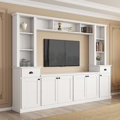 a white entertainment center with built in bookshelves and cabinets on each side, along with a flat screen tv mounted to the wall