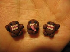 three small brown bears with teeth and tongues on their mouths, sitting in the palm of someone's hand