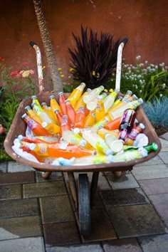 a wheelbarrow filled with lots of different colored candy bars and candles in it