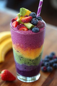 a smoothie with berries, kiwis, and bananas on a wooden table