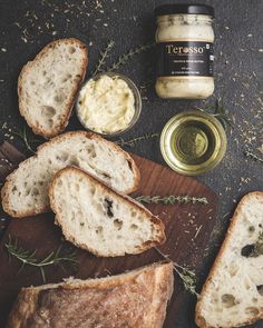 bread, butter and herbs on a cutting board next to a jar of seasoning