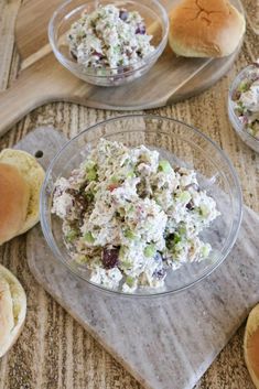 there is a salad in a glass bowl on the table next to rolls and bread