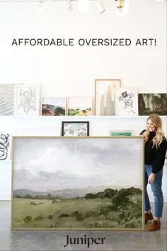 a woman standing next to a large painting