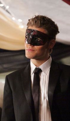 a man in a suit and tie wearing a mask