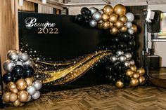 a black, gold and silver balloon arch for a new year's eve party