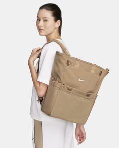 a woman carrying a tan nike tote bag