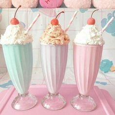 three ice cream sundaes sitting on top of a pink tray