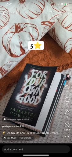 an open book sitting on top of a bed next to a white and orange pillow