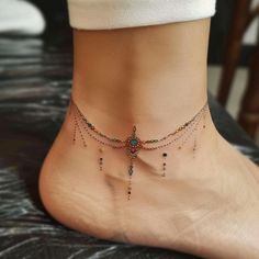 a woman's ankle with beads and chains attached to the side of her foot