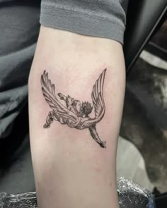 a tattoo on the arm of a person with a bird and flowers in its beak