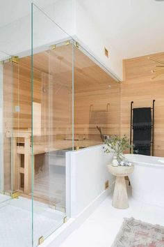 a white bath tub sitting next to a wooden wall with glass doors on the side