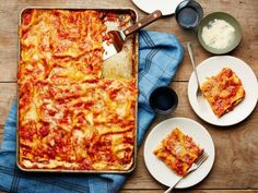 a pizza sitting on top of a wooden table next to plates and utensils