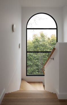 the stairs lead up to an open window in a house with wood floors and white walls