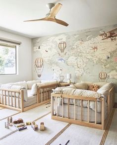 a baby's room with two cribs and a map on the wall