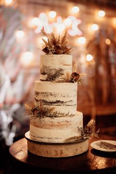 a three tiered cake sitting on top of a wooden table with lights in the background