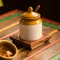 there is a small jar with a spoon in it on the table next to a bowl