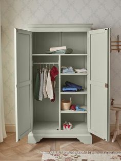 an open white cabinet with clothes hanging on it