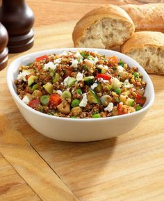 a bowl of food sitting on top of a wooden cutting board next to some bread