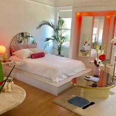 a white bed sitting in a bedroom next to a table with flowers on top of it