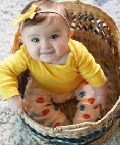 a baby sitting in a basket on the floor