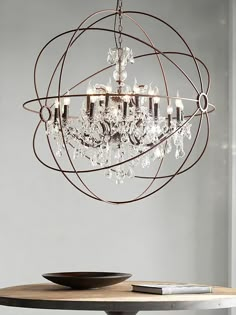 a chandelier hanging from the ceiling in a room with a wooden table and white walls