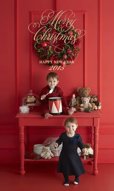 two children sitting on a red table with christmas decorations