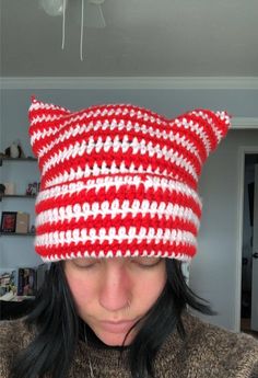 a woman wearing a red and white knitted cat hat