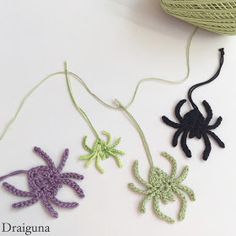 three crocheted spider ornaments on a white surface next to a ball of yarn