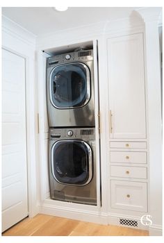 a washer and dryer in a room with white cabinets on either side of the door