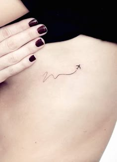 a woman's stomach with a small arrow tattoo on her left side ribcage