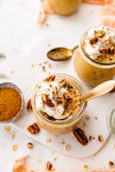 two jars filled with dessert and topped with whipped cream, pecans, and cinnamon