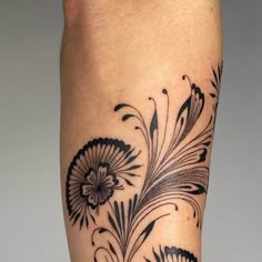 a close up of a person's leg with tattoos on it and flowers in the middle