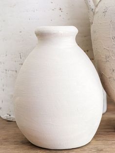 two white vases sitting next to each other on a table