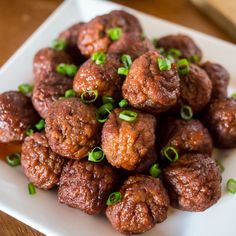 a white plate topped with meatballs covered in green onions