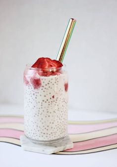 a glass filled with oatmeal and strawberries on top of a table