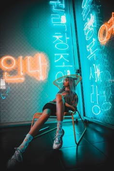 a woman sitting in a chair with neon signs behind her