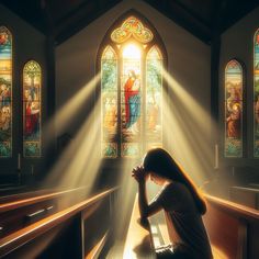 a woman kneeling in front of a stained glass window with the light coming through it