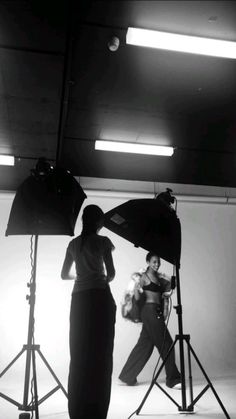 black and white photograph of two women in front of camera equipment, one holding a microphone