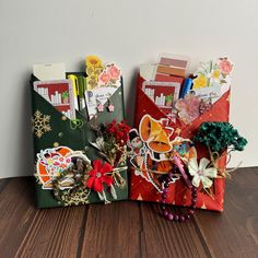 three small envelopes are sitting on a table with some flowers and cards in them