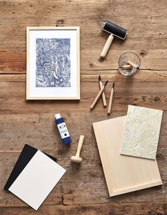 some art supplies are sitting on a wooden table next to a glass and ink pen