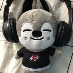 a stuffed animal wearing headphones on top of a white sheet covered floor with black and gray ear muffs