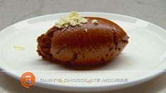 a white plate topped with a piece of chocolate covered pastry on top of a table