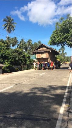 people walking down the street in front of a small hut