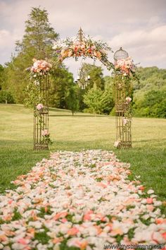 an outdoor wedding ceremony with flowers on the aisle and birdcages in the air