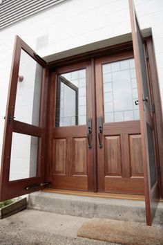 two wooden doors are open in front of a house