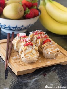 some food is sitting on a cutting board with chopsticks and strawberries in the background