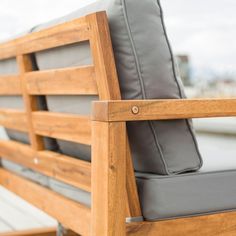 a wooden bench with grey cushions on it